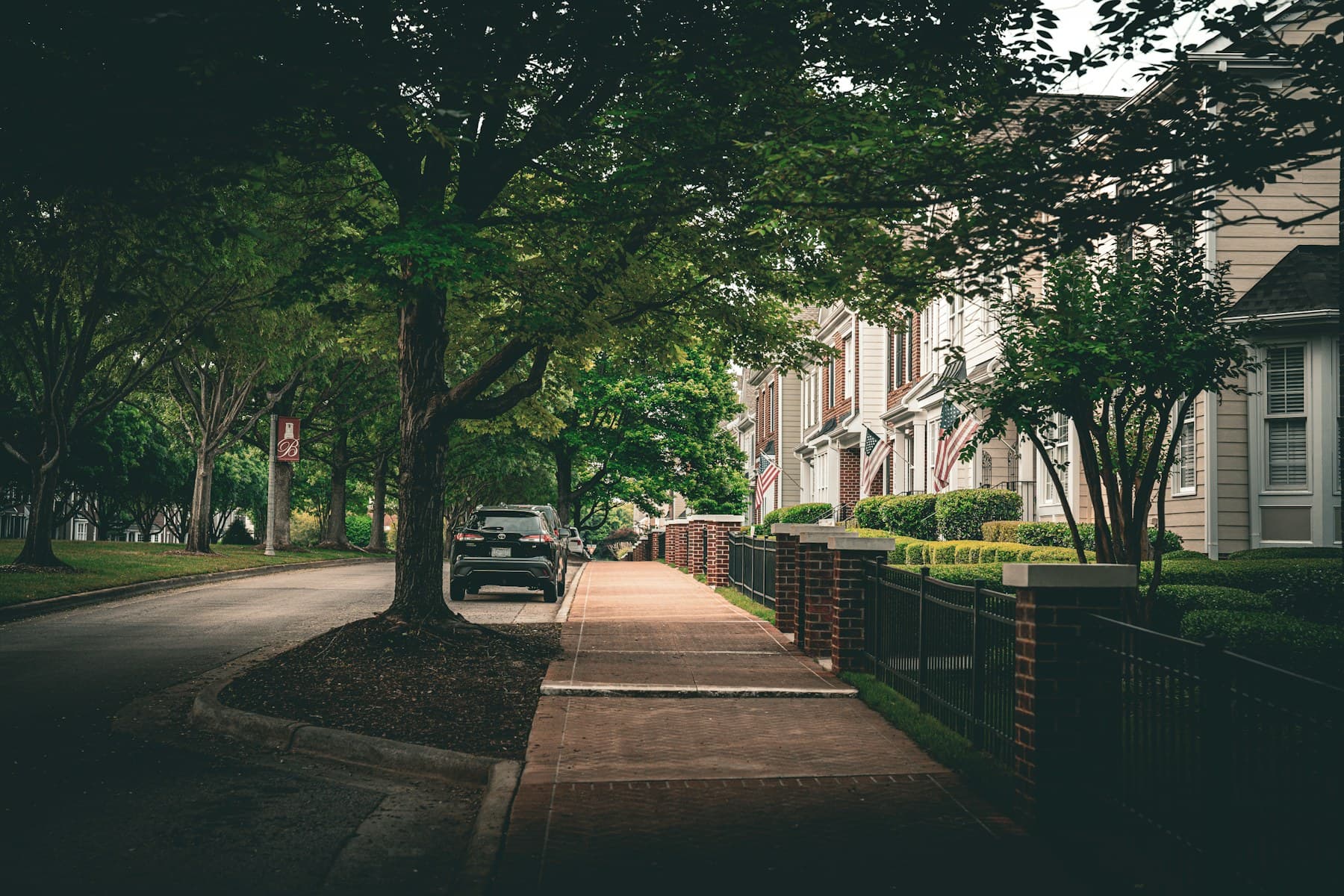 Tree-lined residential street with homes and a pedestrian walkway